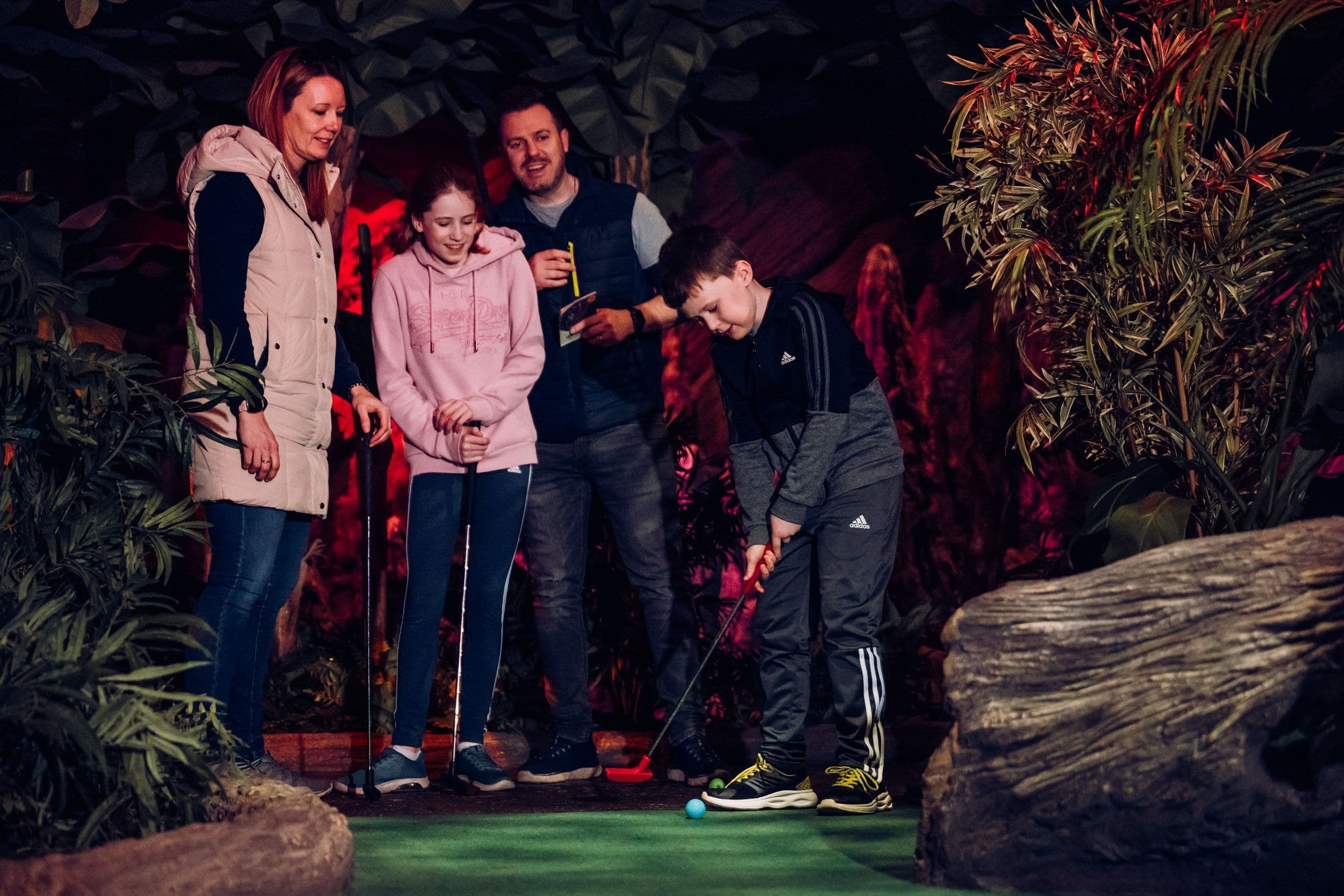 A family of 4 playing mini golf at Treetop Golf.