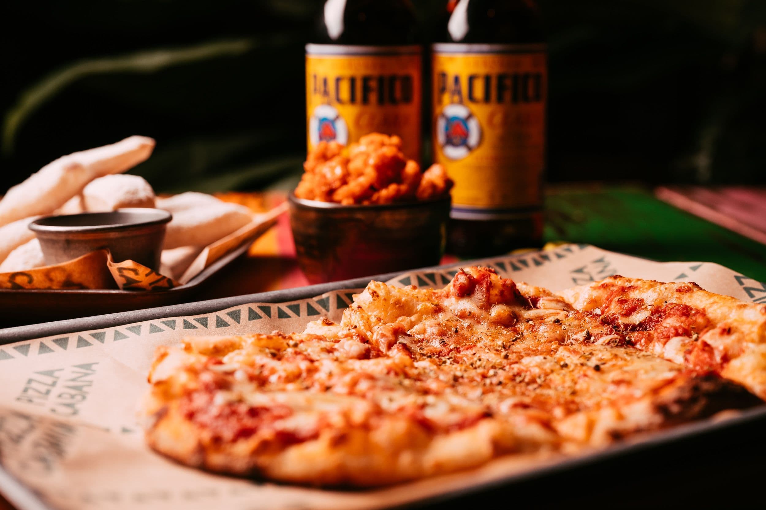 A pizza displayed with sides at Treetop Golf.